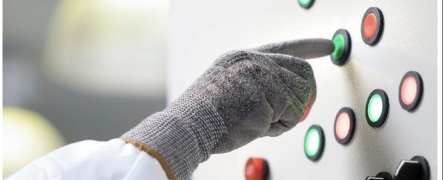 Operario accionando el panel de control eléctrico de un sistema automatizado